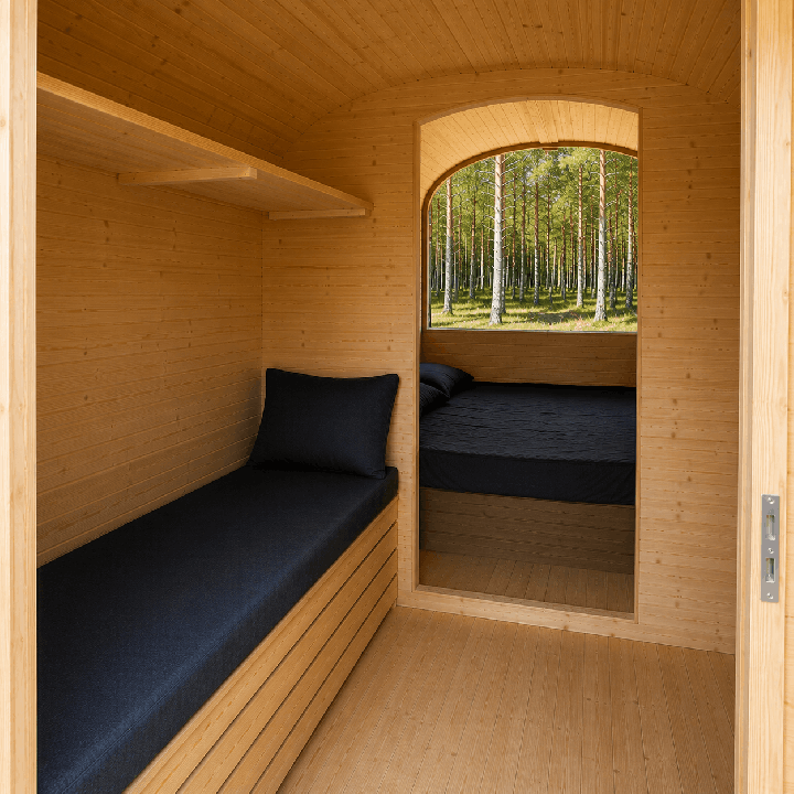Intérieur du pod de camping en bois avec banquette et accès à l’espace nuit.